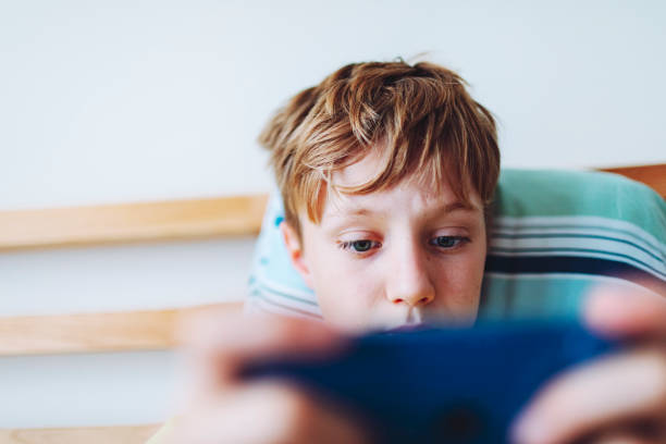 istock School age boy playing video game using mobile at home lying down on bed 1534588606