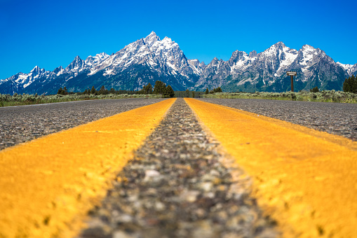 Yellow highway dividing lines with beautiful landscape from Grand Teton National Park