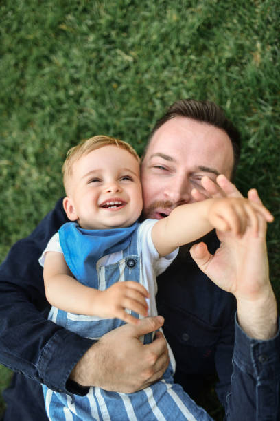 istock Baby Boy Embraced By Father In Park Grass And Lying Down 1534662905