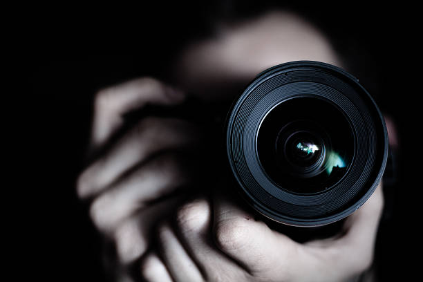 Photographer A photographer with a camera. Focus is on the lens. camera photographic equipment stock pictures, royalty-free photos & images