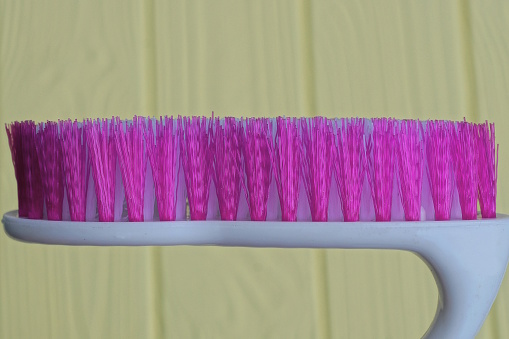 one white plastic brush with purple bristles on a yellow background