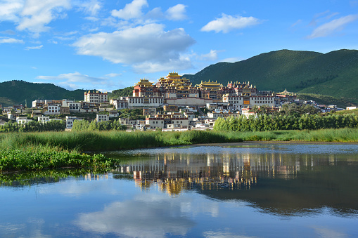 Beautiful view of the Ganden Sumtseling Temple reflecting in the water. Zhongdian (Shangri-La), China