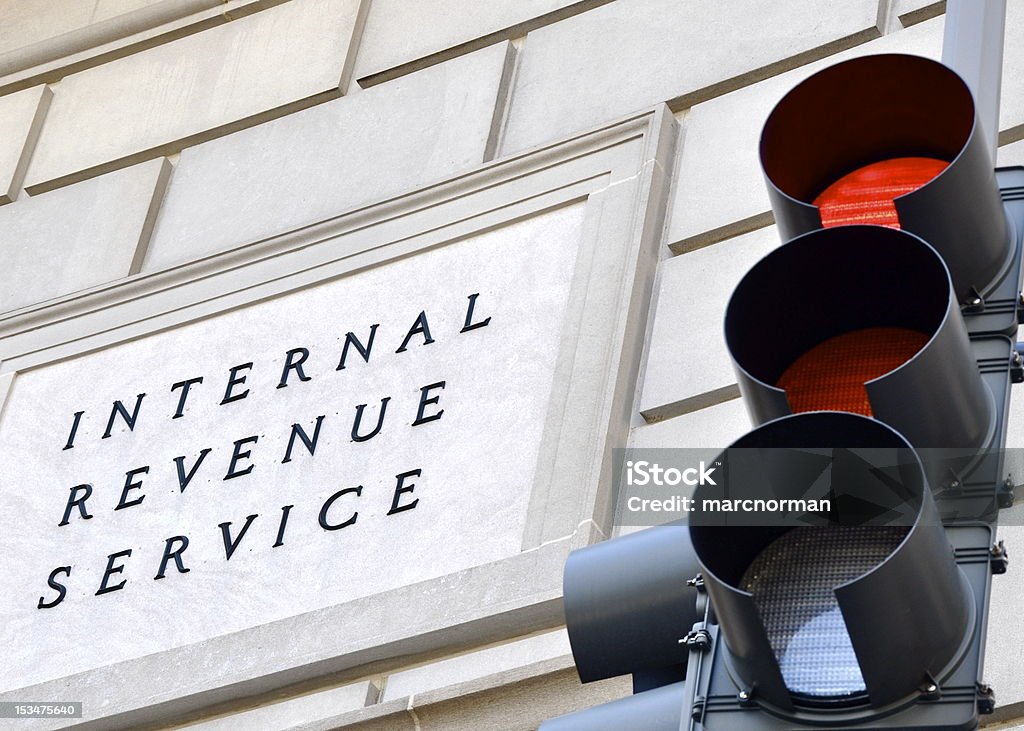 Stop, pay your taxes! Internal Revenue Service sign with a traffic signal in the foreground indicating a red light. Internal Revenue Service Stock Photo