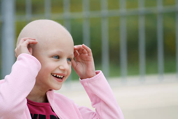 Smiling child cancer patient in pink beautiful caucasian girl undergoing chemotherapy treatment for cancer in her kidney completely bald stock pictures, royalty-free photos & images