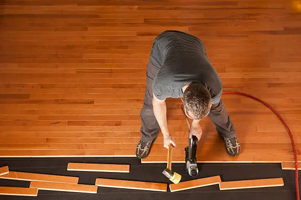 Photo of Man installing a wood floor shown from above