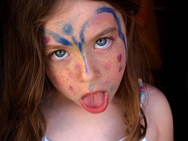 a cute blond little girl sticking her tongue out