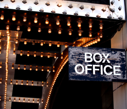 A distressed box office sign under the marquee of a downtown theatre