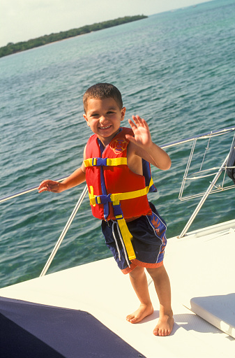 Boy with life jacket standing on deck of a boat, Florida Keys, USA