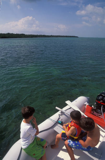 Three boys fishing on a rubber dinghy, Florida Keys, USA