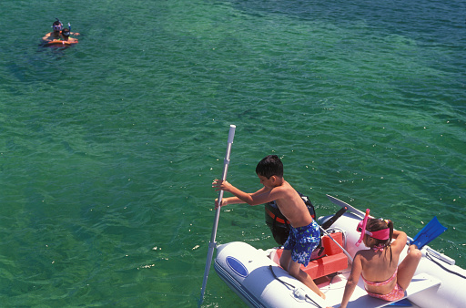 One boy and one girl having fun on a rubber boat by a pier, Florida Keys, USA