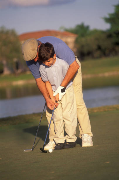 Grandfather teaching his grandson how to play golf, Miami, Florida USA