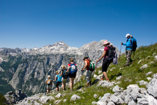 Two men and five women hiking in mountains. They walking one after the other. Magnificent scenery. Peaceful nature.