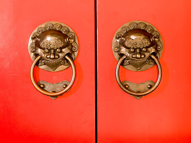Double Demons Traditional Chinese demon-designed door knockers guarding auspiciously red coloured doors. chinese temple dog stock pictures, royalty-free photos & images
