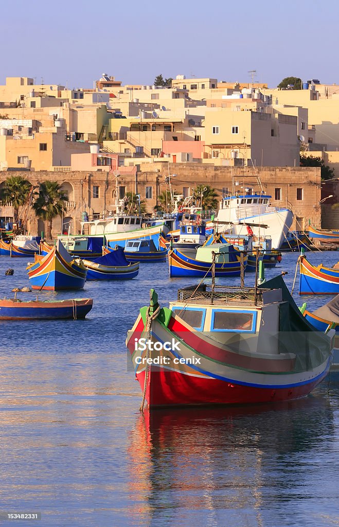 Marsaxlokk Fishing Village Colorful, traditional fishing boats against the backdrop of Marsaxlokk village in the mediterranean island of Malta. Copyspace at top and bottom. See portfolio for more. Malta Stock Photo
