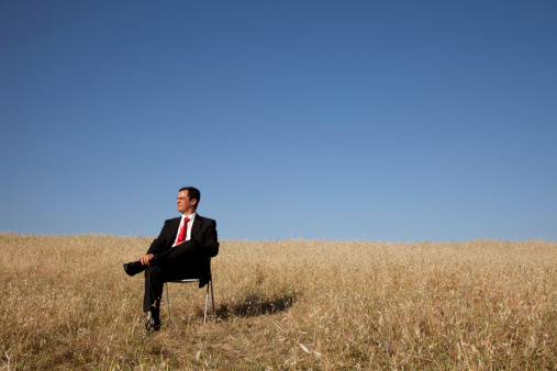 businessman sitting in a chair in outdoor looking to the field