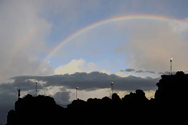 Photo of Rainbow ,torches and person at dusk in Kaanapali.Maui.