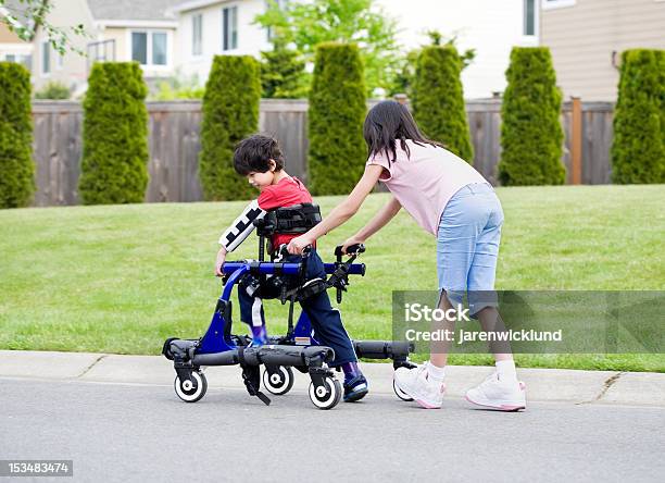 Big Sister Helping Younger Disabled Brother In Walker Stock Photo - Download Image Now