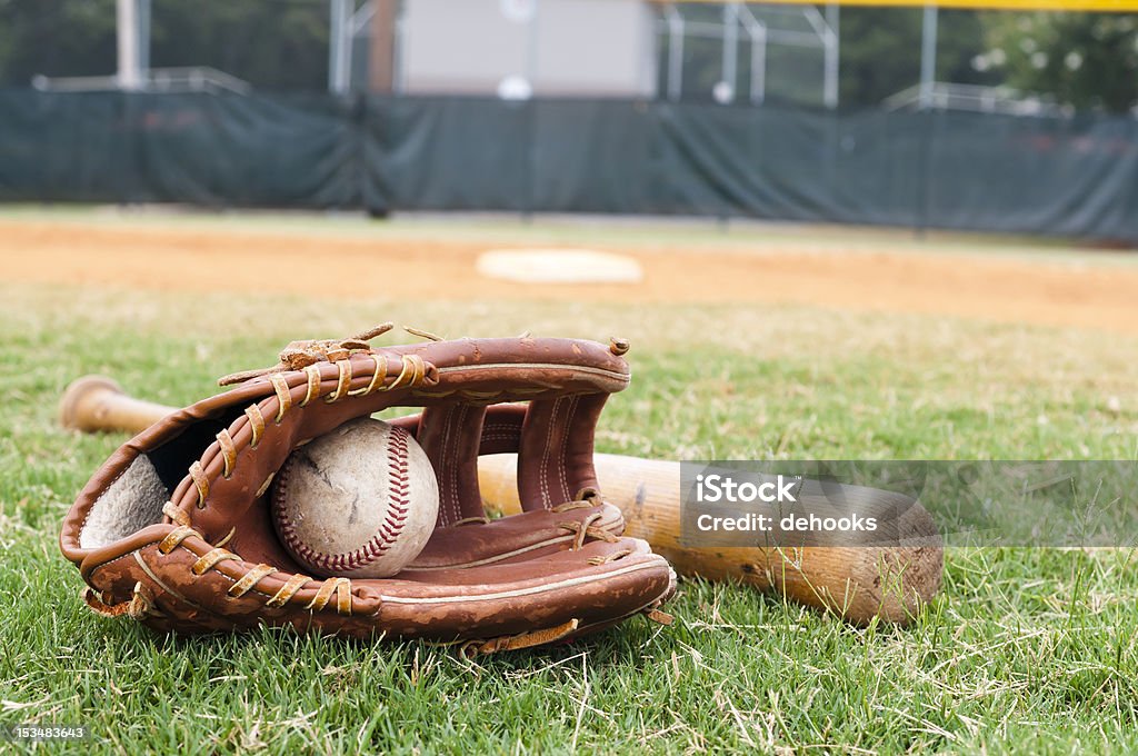 Old Baseball, Glove, and Bat on Field Old baseball, glove, and bat on field with base and outfield in background. Baseball Glove Stock Photo