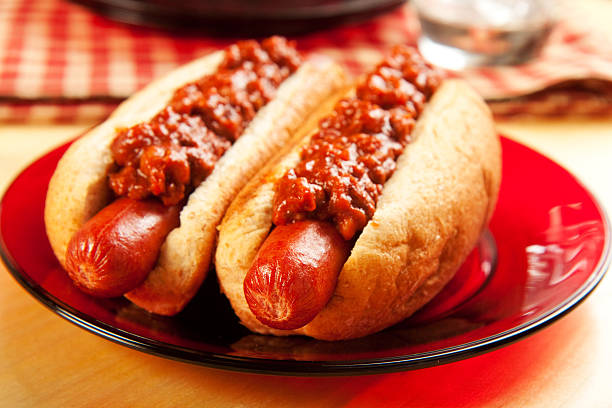 Two chili dogs on a red plate at a picnic stock photo