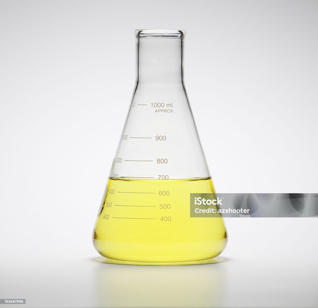 Laboratory Glassware Large laboratory flask filled with yellow liquid on a white background. Half Full Stock Photo