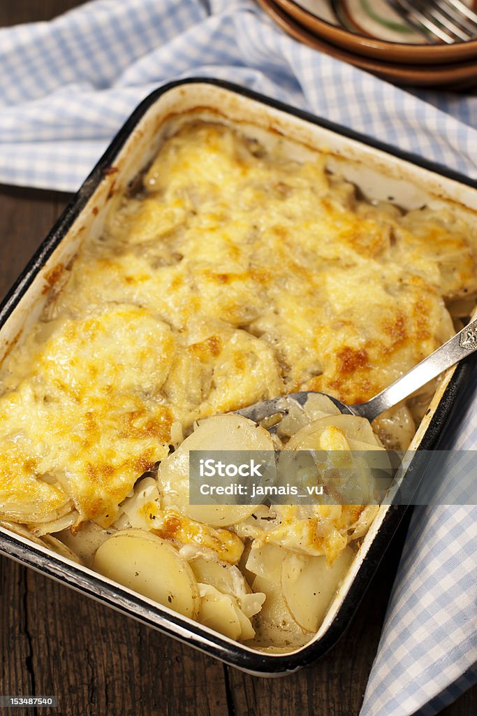 Potato gratin dauphinoise Potato gratin dauphinoise in the pan on rustic background Baked Stock Photo