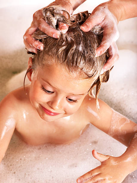 Kid washing hair by shampoo . stock photo