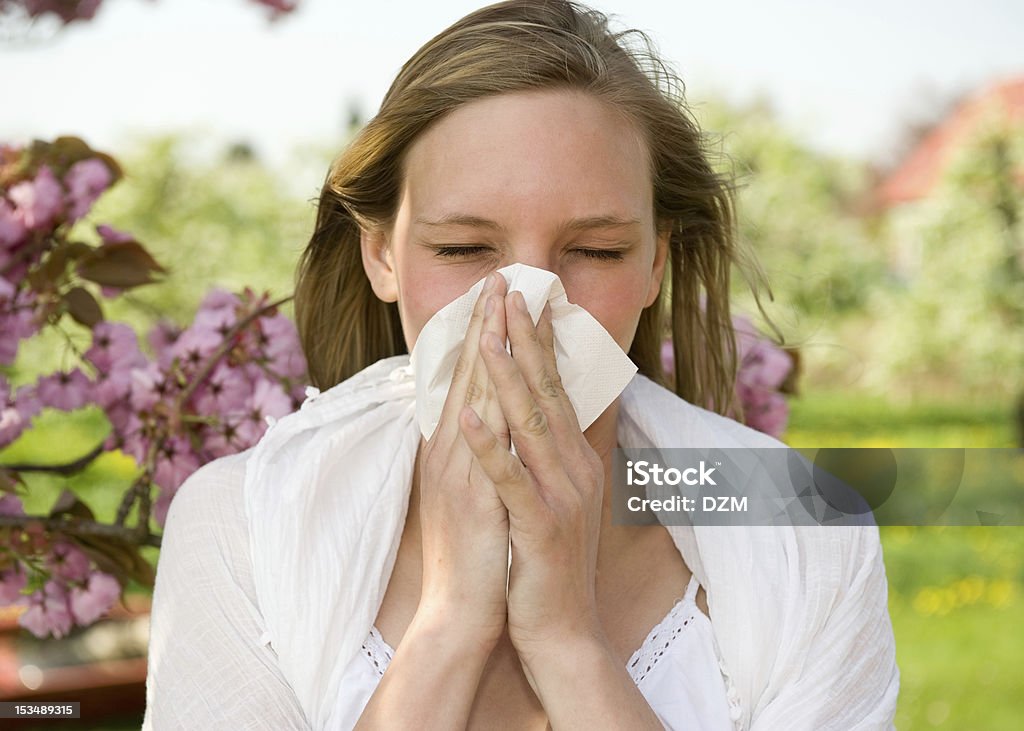 A young girl sneezing into a tissue Allergic girl sneezing in handkerchief Adult Stock Photo