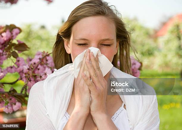 A Young Girl Sneezing Into A Tissue Stock Photo - Download Image Now - Adult, Adults Only, Allergy