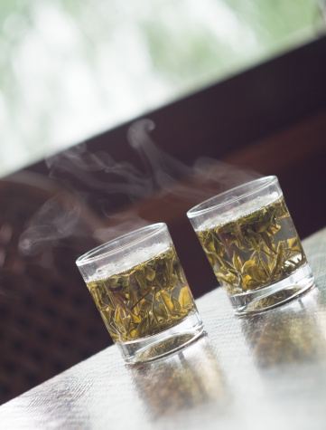 Glass of Chinese green tea on the table with steam at restaurant in Hangzhou, Xihu Lake, China