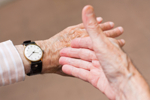 Elderly man pointing at his watch, showing the time.