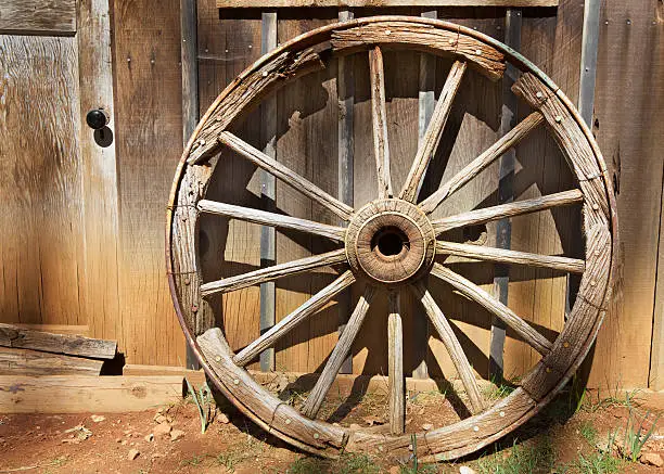 Old Wagonwheel  in strong sunlight against a barn wall