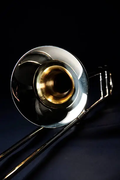 A gold brass trombone isolated against a black background in the vertical format.