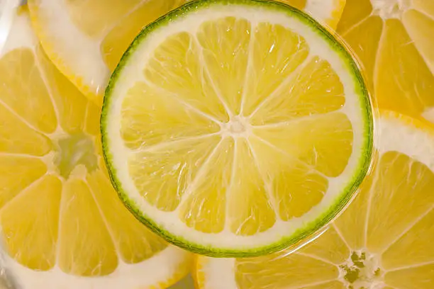 Slices of lemons and limes photographed while floating in lemonade. Photographed using daylight and strobes. Focus limited primarily to the lime.