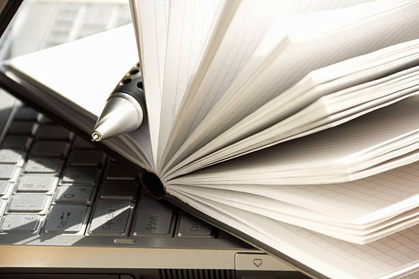 Journal with pen on top of a laptop