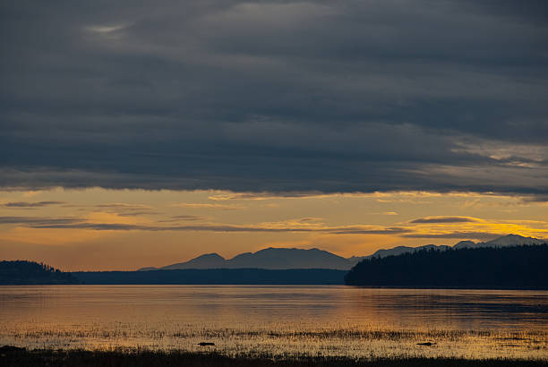 Sunset and Storm Clouds Over Skagit Bay The landscapes and seascapes of Puget Sound are a constant source of inspiration for photographers. This picture of a sunset was photographed from the North Fork Access near La Conner, Washington State, USA. jeff goulden puget sound stock pictures, royalty-free photos & images