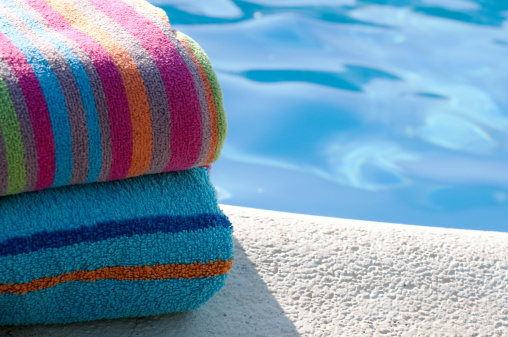 Colourful towels folded by side of swimming pool
