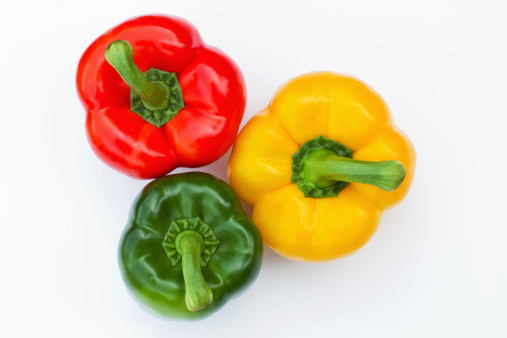 three bell peppers in red, green and yellow on white background