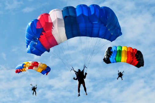 three colorful parachutes on blue sky.