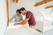Attractive Hispanic Couple Building A Crib In A White Room