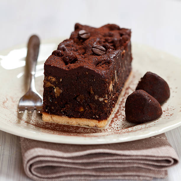 piece of chocolate cake and chocolate truffles with cocoa on a plate