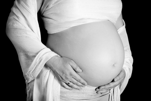 Closeup of an eight months pregnant woman holding her tummy in her hands