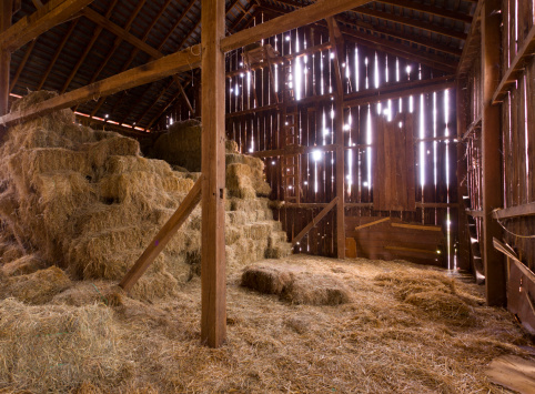 HDR image of an old Barn with the sun streaming from outside and straw and hay on the floor of the hayloft