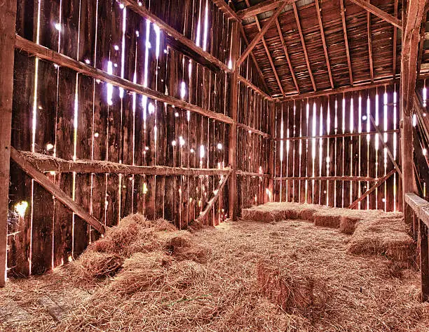 HDR image of an old Barn with the sun streaming from outside and straw and hay on the floor of the hayloft