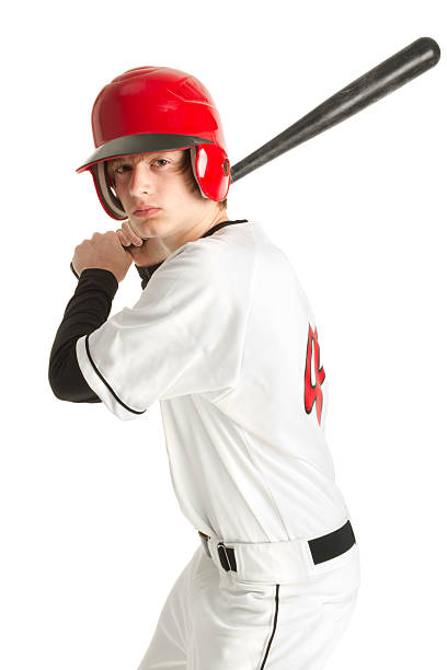 Teenage baseball player in uniform Teenage baseball player in a red, white and black baseball uniform, wearing a red baseball helmet. Baseball player is in ready position to hit the ball; he is holding the bat over his shoulder. Isolated on white. baseball player photos stock pictures, royalty-free photos & images