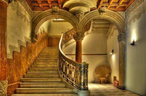 Boston, Massachusetts, USA - February 1, 2024: View up the Grand Staircase (aka Main Staircase) of the Massachusetts State House. Near the top of the staircase is a stained glass window showing the evolution of the Commonwealth of Massachusetts' state seal.