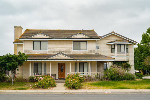 An old house with a beautifully landscaped front of yard, and a cloudy sky in the background, somewhere in California. Santa Maria, California, USA - 07/06/2023