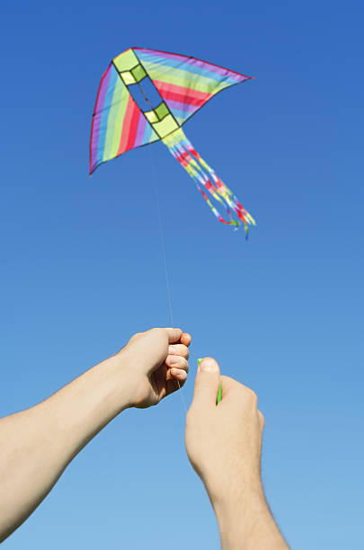 istock closeup of mans hands flying multicolored kite 153507772