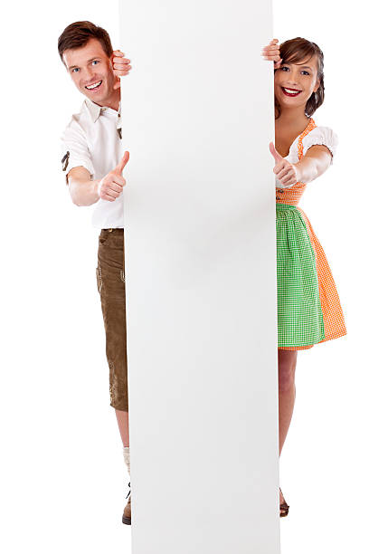 Young happy couple stand behind billboard and show thumbs up stock photo