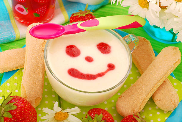 A female hand on a wooden bench eats a strawberry dessert with cream for breakfast.