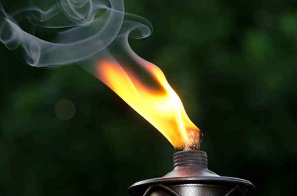 Smokin' Flame and gently curling smoke from an outdoor tiki torch. tiki torch stock pictures, royalty-free photos & images